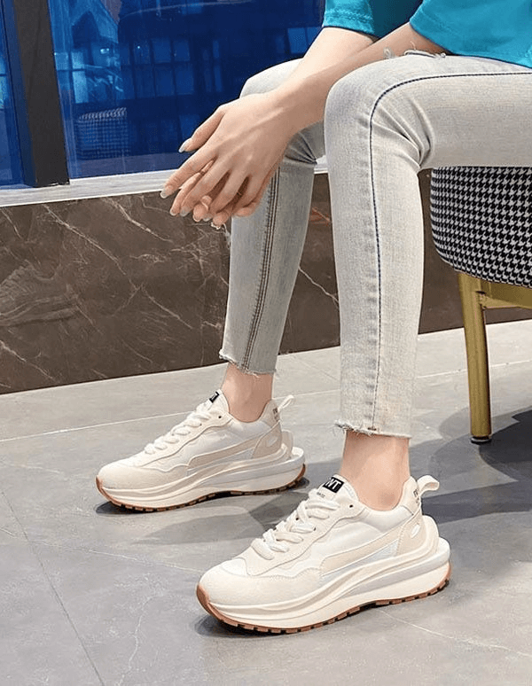 Stylish women's everyday sports sneakers with platform, featuring suede uppers and mesh lining, worn by a seated individual.